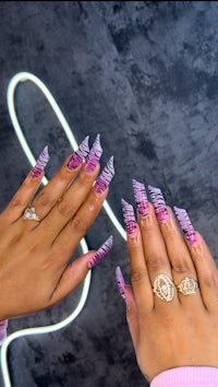 a woman's pink and purple nails with a neon light in the background